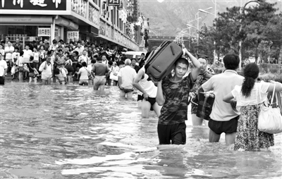 昨日，一名消防戰(zhàn)士在秦皇島市山海關(guān)火車站站前廣場(chǎng)涉水幫助旅客運(yùn)送行李。 新華社發(fā)