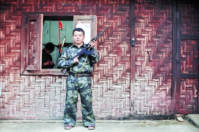 老三手持自己在前線用的半自動(dòng)步槍站在居住的小屋外。