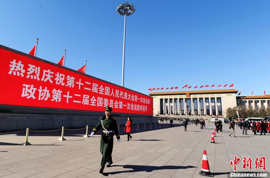 3月4日，北京晴空萬(wàn)里，武警從北京天安門(mén)廣場(chǎng)大型顯示屏前走過(guò)。3月5日上午，十二屆全國(guó)人大一次會(huì)議將隆重開(kāi)幕。中新社發(fā) 劉忠俊 攝